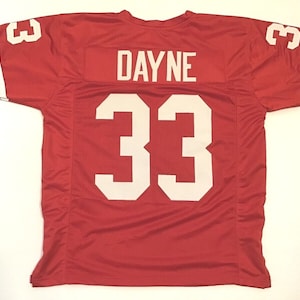 May include: Red football jersey with white lettering. The jersey has the number "33" and the name "DAYNE" on the back.
