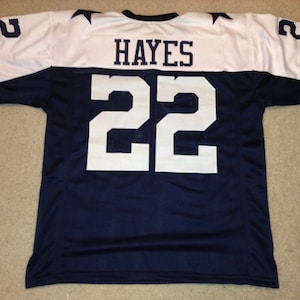 May include: A navy blue football jersey with white sleeves and white lettering. The jersey has the number "22" and the name "HAYES" on the back.