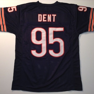 May include: A navy blue football jersey with white and orange stripes on the sleeves. The number 95 is printed on the back of the jersey in white with a red outline. The name "DENT" is printed above the number in white.