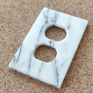 Pode incluir: Um conjunto de três canecas de cerâmica com acabamento fosco e salpicado. As canecas são em tons de creme, cinza claro e cinza escuro. Cada caneca tem um design simples e minimalista e uma alça arredondada.