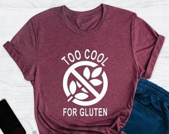May include: A heather maroon t-shirt with a white graphic that says "Too Cool For Gluten" with a crossed-out wheat symbol.