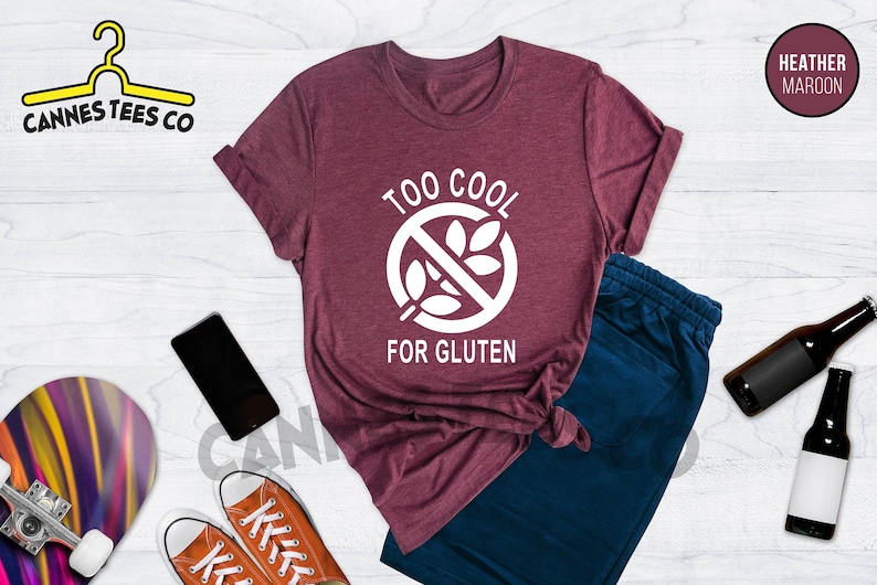 May include: A heather maroon t-shirt with a white graphic that says "Too Cool For Gluten" with a crossed-out wheat symbol.