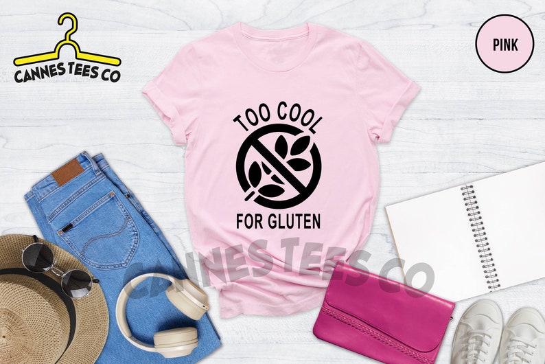 May include: Pink t-shirt with a black graphic that says "Too Cool For Gluten" and a crossed-out wheat symbol.
