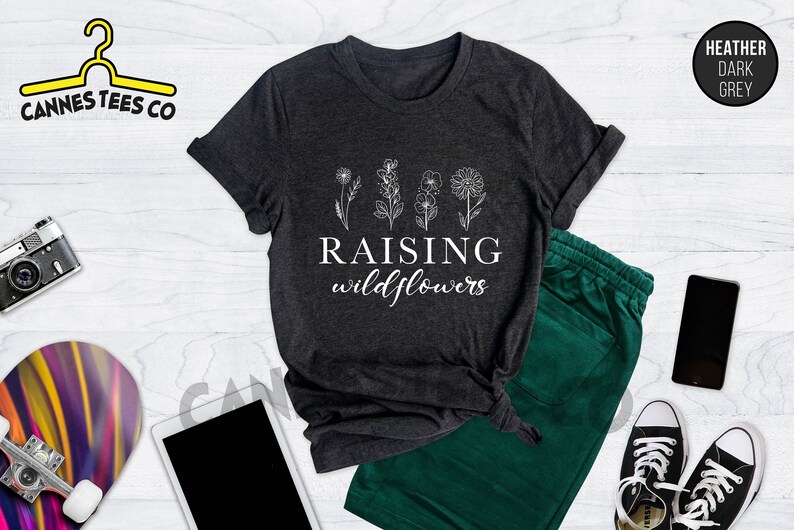 K&ouml;nnte beinhalten: Heather dunkelgraues T-Shirt mit einer wei&szlig;en Grafik von Blumen und dem Text "Raising wildflowers".