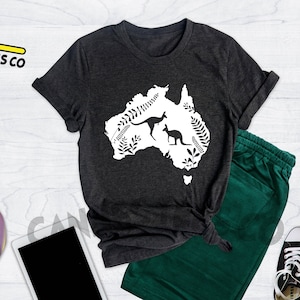 Może przedstawiać: Szary t-shirt w kolorze ciemnego melanżu z białym nadrukiem przedstawiającym zarys Australii z dwoma kangurami w środku. Nadruk jest otoczony białymi wzorami kwiatowymi.