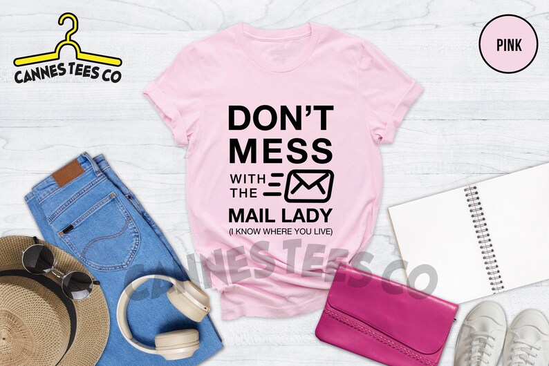May include: Pink t-shirt with black text that reads "Don't Mess With The Mail Lady (I Know Where You Live)" and a black envelope graphic.