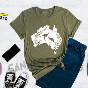 Może przedstawiać: Zielona koszulka z białym obrysem kontynentu Australii z dwoma kangurami w środku. Tekst "Cannes Tees Co" znajduje się w lewym g&oacute;rnym rogu obrazu. Tekst "Heather Olive" znajduje się w prawym g&oacute;rnym rogu obrazu.