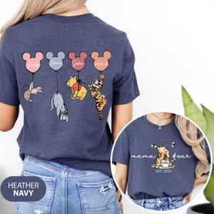 May include: A heather navy blue t-shirt with a Winnie the Pooh and friends design. The shirt features four characters holding balloons with names on them. The back of the shirt says "mama bear est. 2025".