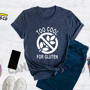 May include: A heather navy blue t-shirt with a white graphic that says "Too Cool For Gluten" with a crossed-out wheat symbol.