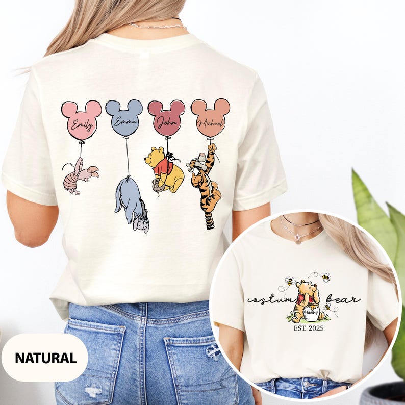 May include: A white t-shirt with a design of Winnie the Pooh and friends holding balloons with names on them. The back of the shirt says "custom bear est. 2025".