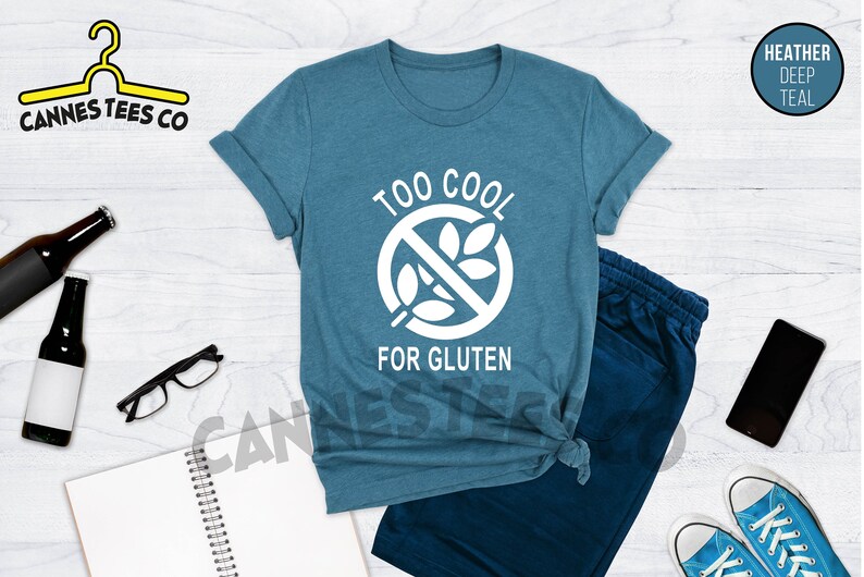 May include: A teal blue t-shirt with a white graphic of a crossed-out wheat stalk and the text "Too Cool For Gluten".