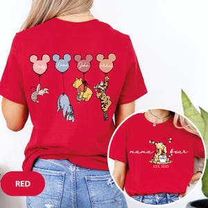 May include: Red t-shirt with a Winnie the Pooh and Tigger design. The shirt features five Mickey Mouse balloons with names written on them. The back of the shirt says "mama bear est. 2025".