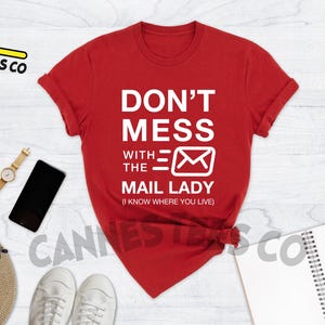 May include: Red t-shirt with white text that reads "Don't Mess With The Mail Lady (I Know Where You Live)".
