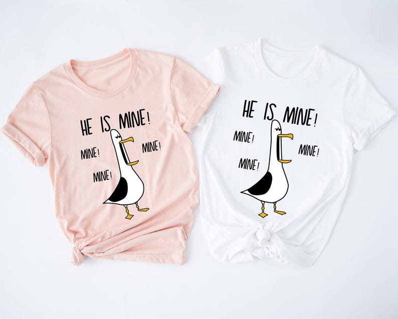 May include: Two t-shirts with a cartoon seagull graphic and the text "He is mine!" repeated multiple times. The shirts are pink and white.