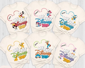 May include: Six white t-shirts with a Mickey Mouse ear design and the text "My First Disney Trip". Each shirt has a different character from Disney, including Mickey Mouse, Minnie Mouse, Donald Duck, Goofy, Pluto, and Daisy Duck. The shirts are all in a natural color.