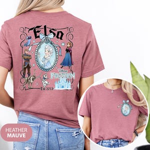 May include: Heather mauve t-shirt featuring a graphic of Elsa from Disney's Frozen. The design includes Elsa's image, other characters, and the text "Elsa" and "Frozen". The shirt also has the text "Est. 2013".