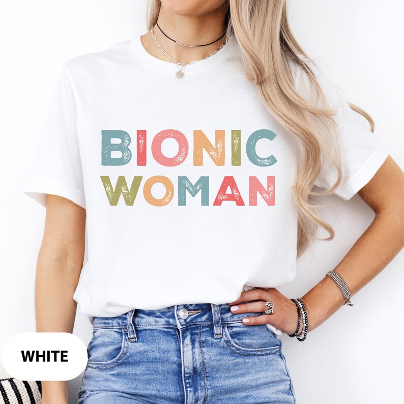 May include: White t-shirt with the text "Bionic Woman" in colorful, distressed lettering.