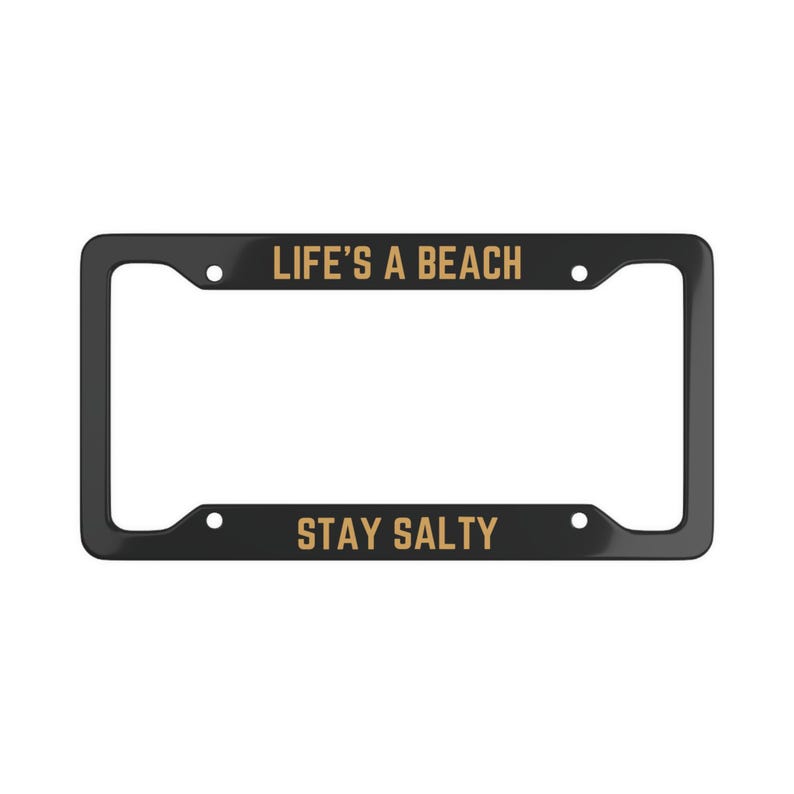 May include: Black license plate frame with gold text that reads "LIFE'S A BEACH" on the top and "STAY SALTY" on the bottom.