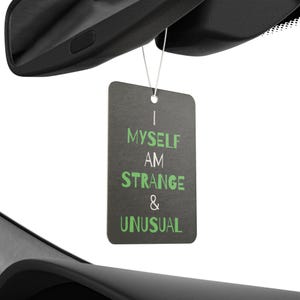 May include: Black car air freshener with the text "I Myself Am Strange & Unusual" in white and green lettering.