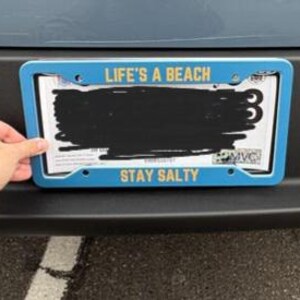 May include: Blue license plate frame with the text "Life's a Beach" and "Stay Salty" in yellow lettering.
