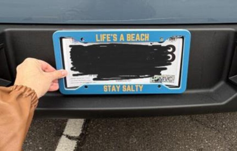 May include: Blue license plate frame with the text "Life's a Beach" and "Stay Salty" in yellow lettering.