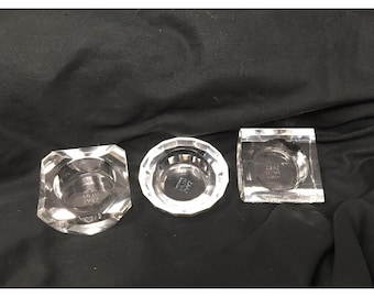 Juego de tres portavelas de cristal de Saks Fifth Avenue con diferentes formas.