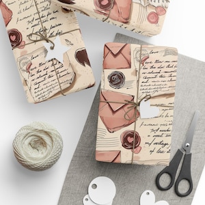 Peut inclure: Des cadeaux emballés avec du papier imprimé de lettres d'amour vintage, de timbres et d'enveloppes. Les cadeaux sont attachés avec de la ficelle et ont des étiquettes. Une pelote de ficelle, des ciseaux et des étiquettes sont également présents.