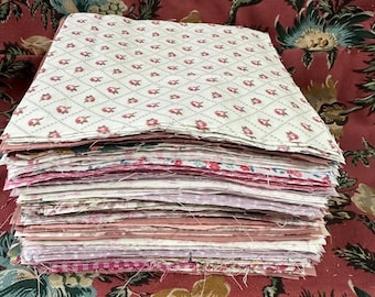 Pode incluir: Uma pilha de quadrados de tecido rosa e branco, com um padrão floral no quadrado superior. Os quadrados de tecido estão dispostos em uma pilha organizada, e o quadrado superior está dobrado sobre o resto da pilha.