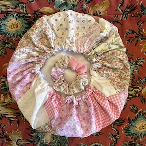 May include: A pink and white patchwork fabric shower cap with a pink scrunchie inside.