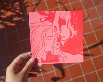 May include: A pink card with a line drawing of two women facing each other. The women have long hair and are drawn in a simple style.