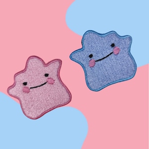 以下が含まれることがあります： Dittoのキャラクターの形をした2つの刺繍パッチ。1つはピンク、もう1つは青です。どちらも黒い目、笑顔の口、ピンクの頬をしています。背景はピンクと青です。