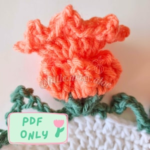 May include: A crocheted flower with a peach coloured bloom and green leaves. The flower is sitting on top of a white crocheted fabric. The text "PDF ONLY" is written on a green rectangle with a pink flower.