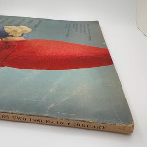 May include: A vintage magazine cover featuring a woman wearing a red dress. The cover text reads "Two Issues in February".