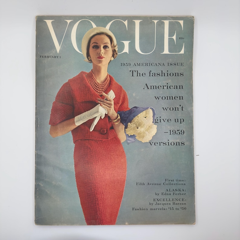 Vogue magazine Feb 1,1959. Elegant women wearing a red fitted wool suit. she is holding a white glove and a bouquet of white peonies. She is standing center of the magazine. With a description on one side. ''Fashion American women won't give up 1959"