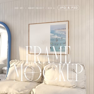 Peut inclure: Une maquette de photo encadrée avec une scène de plage. Le cadre est sur un mur blanc avec des lambris en bois. La photo représente une plage avec des gens qui nagent et font du surf. Le cadre est posé sur un canapé blanc avec deux coussins.