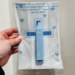May include: A blue crayon with the word "Crayola" printed on it, packaged in a clear plastic bag with a white card. The card has a blue cross and hearts printed on it. The card also has a bible verse printed on it: "Jesus said, 'Let the little children come to me, and do not hinder them. For the kingdom of heaven belongs to such as these.' Matthew 19:14"