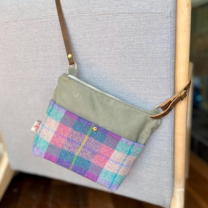 Peut inclure: Un sac bandoulière composé d'une partie supérieure en toile vert sauge et d'une partie inférieure en tissu à carreaux multicolore dans des tons rose, violet et bleu sarcelle. Le sac possède une sangle réglable en cuir marron et des ferrures dorées.