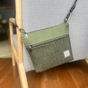 Peut inclure: Un sac bandoulière composé d'une partie supérieure en toile vert olive et d'une partie inférieure à motif chevrons vert foncé et noir. Le sac comprend une poche frontale zippée, une fermeture éclair supérieure et une bandoulière noire réglable.