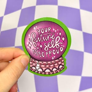 May include: A green and pink sticker with a magic eight ball design. The text inside the ball reads "Your future self is so proud".