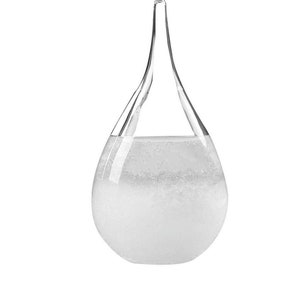 May include: A clear glass weather forecaster in a teardrop shape. The glass vessel has a long, slender neck and is filled with a clear liquid that has a cloudy, crystallized appearance in the lower portion. The background is plain white.