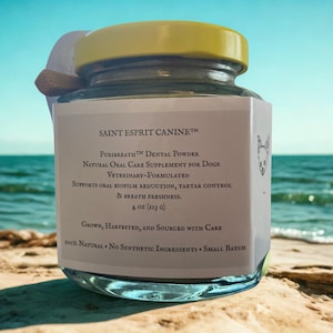 May include: A glass jar with a yellow lid, labeled "SAINT ESPRIT CANINE" and "Puribreath Dental Powder" for dogs. The label also states the product is natural and supports oral health. The jar is on a sandy surface with the ocean in the background.