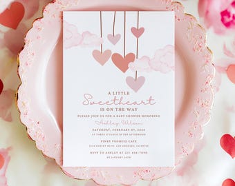 May include: A white rectangular baby shower invitation card featuring pink watercolor clouds and hanging heart illustrations. The text reads A Little Sweetheart Is On The Way, Please Join Us For A Baby Shower Honoring Ashley Wilson, Saturday, February 07, 2024.