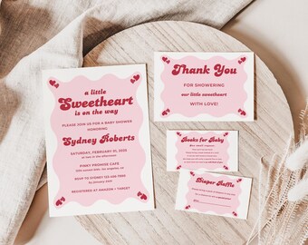 May include: A set of baby shower stationery featuring a pink wavy border with small red hearts. The cards include text for an invitation, a thank you note, a books for baby request, and a diaper raffle ticket, all printed in a retro red font.