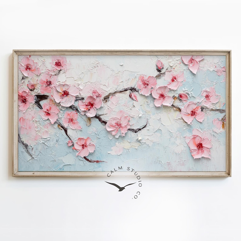 May include: A framed painting of a blossoming cherry tree branch. The artwork features textured, raised pink flowers and dark brown branches against a light blue and white background. The frame is a light wood color.