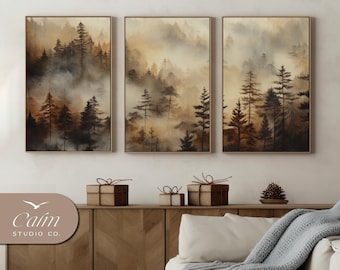 May include: A set of three framed watercolor paintings depicting a misty forest scene with brown and green trees. The paintings are hung on a white wall above a wooden cabinet.