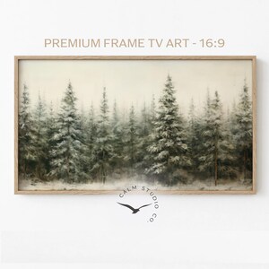 Puede incluir: Una impresi&oacute;n art&iacute;stica enmarcada que presenta una serena escena de bosque con &aacute;rboles de hoja perenne cubiertos de nieve. La obra de arte est&aacute; en un marco de madera rectangular. El texto en la parte superior dice "PREMIUM FRAME TV ART - 16:9". La esquina inferior derecha tiene un logotipo con un p&aacute;jaro y el texto "CALM STUDIO CO."