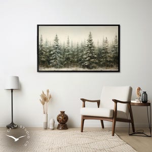 Puede incluir: Una impresi&oacute;n art&iacute;stica enmarcada representa un bosque brumoso de &aacute;rboles de hoja perenne. La obra de arte, con un marco negro, utiliza una paleta de colores apagados de verdes, blancos y marrones, creando una escena natural y serena. La impresi&oacute;n cuelga sobre una silla moderna de mediados de siglo.