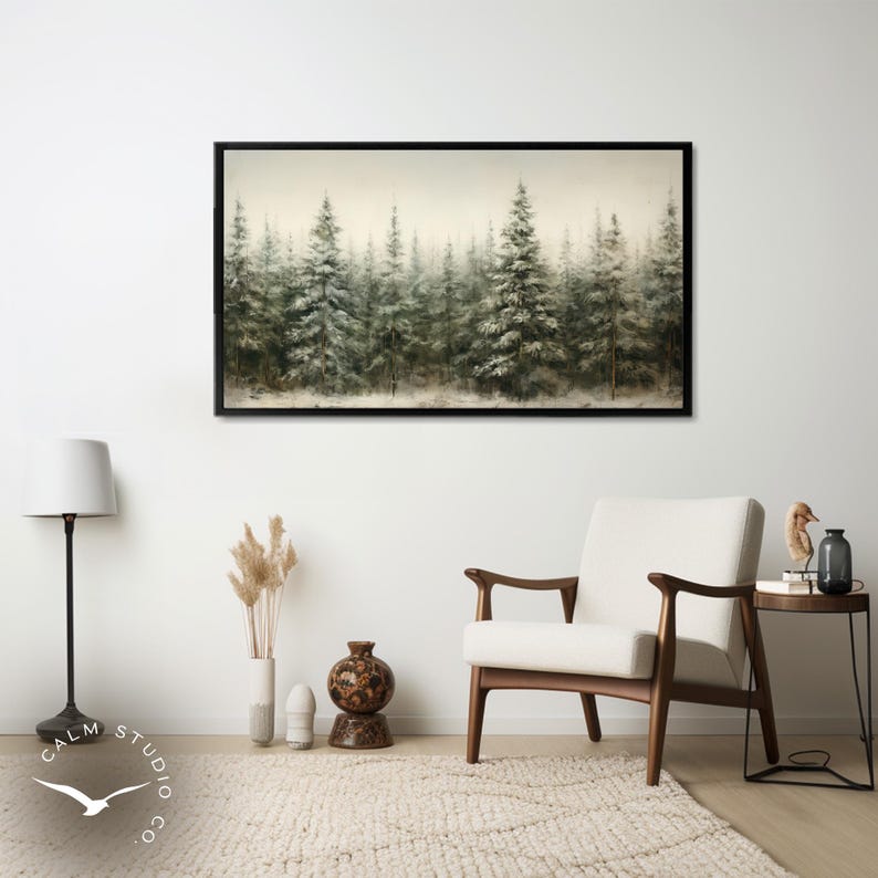 Puede incluir: Una impresi&oacute;n art&iacute;stica enmarcada representa un bosque brumoso de &aacute;rboles de hoja perenne. La obra de arte, con un marco negro, utiliza una paleta de colores apagados de verdes, blancos y marrones, creando una escena natural y serena. La impresi&oacute;n cuelga sobre una silla moderna de mediados de siglo.
