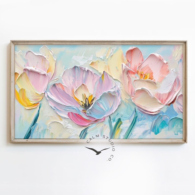 May include: A framed floral painting featuring textured brushstrokes. The artwork showcases large, stylized tulips in shades of pink, yellow, and white against a light blue background. The frame is a light wood color. The painting is signed "Calm Studio co."