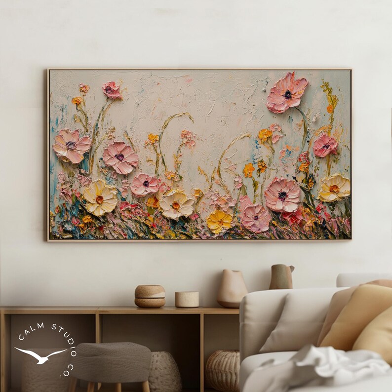 May include: A framed floral painting featuring textured, raised flowers in shades of pink, yellow, and white against a light background. The artwork has a thick, impasto style, with visible brushstrokes. The painting is a rectangular canvas with a gold frame.